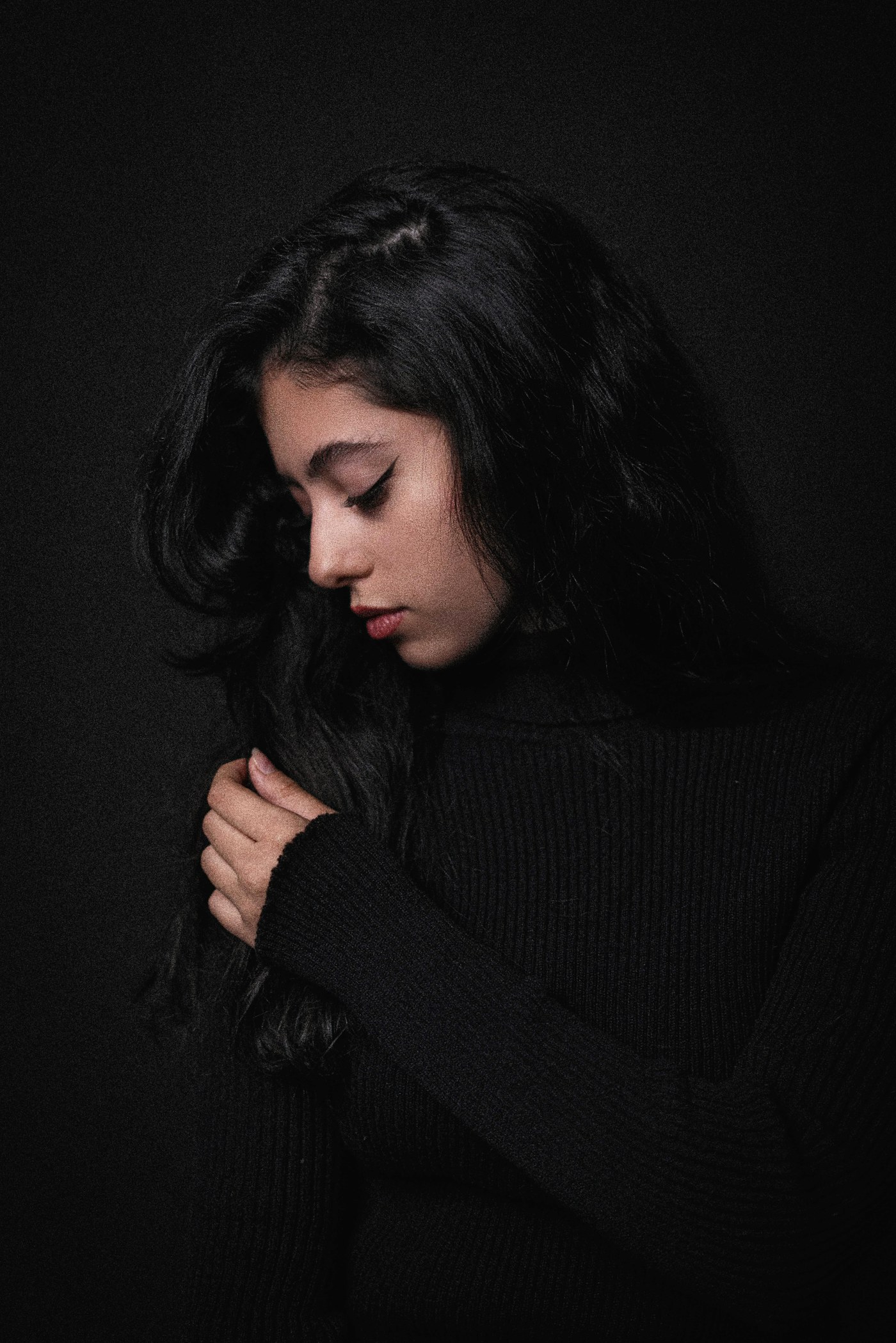 Long dark hair against a black background